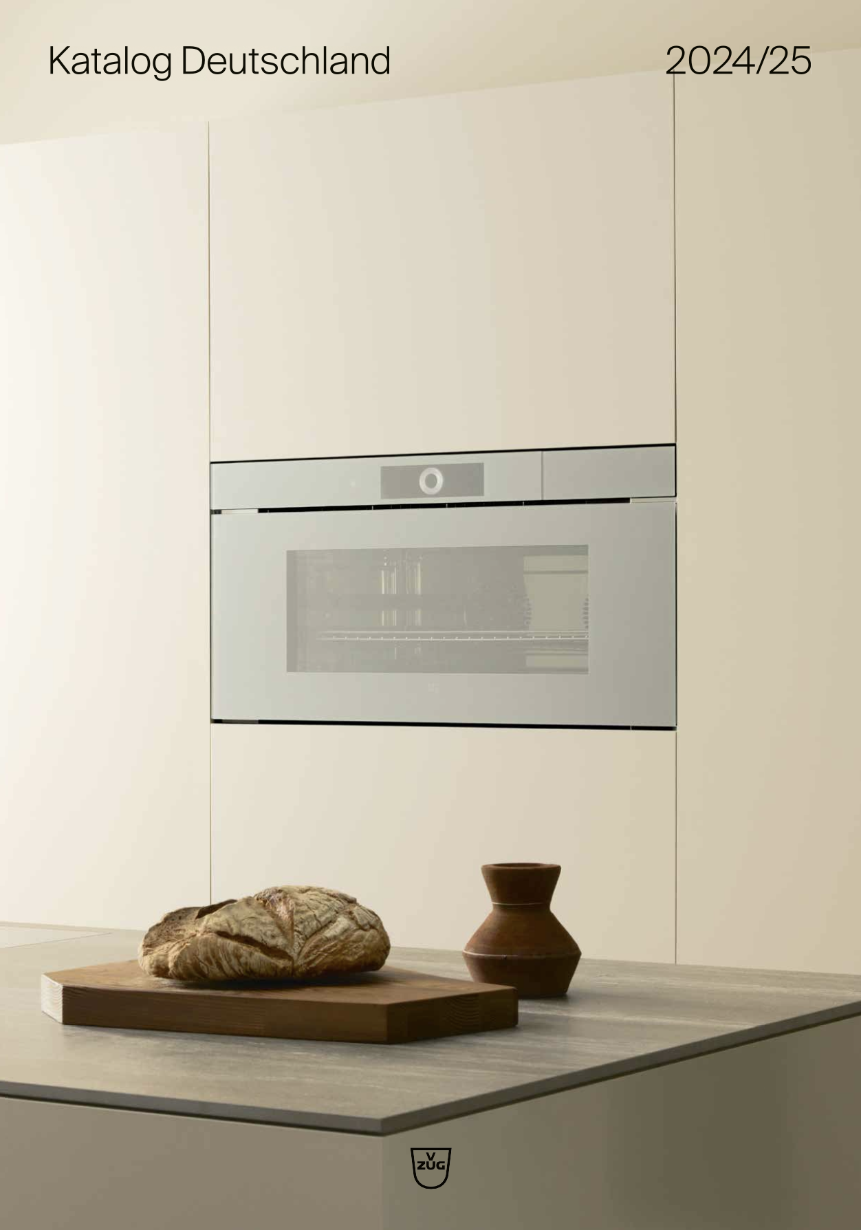 Moderne Küche mit eingebautem Backofen, frischem Brot auf Holzbrett und mattem Keramikgefäß.