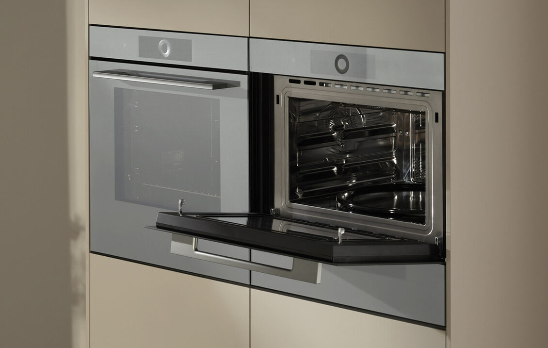 Moderner Küchenbereich mit geschlossenem Backofen und geöffneter Mikrowelle in Edelstahloptik.