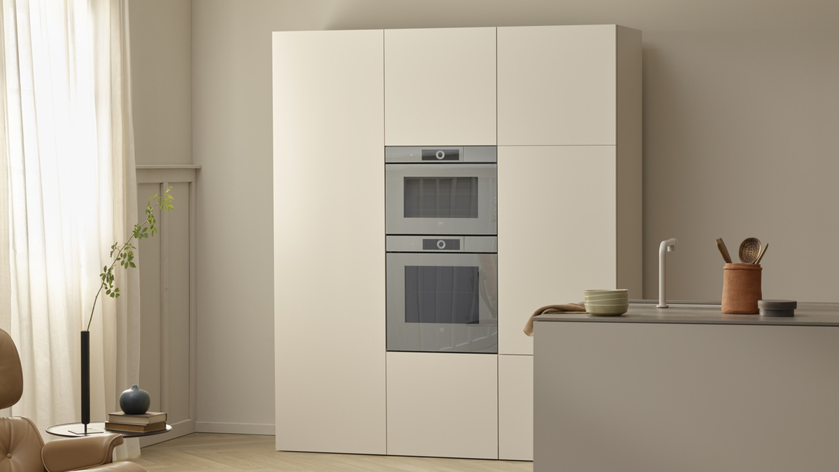 Moderne, minimalistische Küche mit hellen Farben, integrierten Öfen und einer eleganten Kücheninsel.