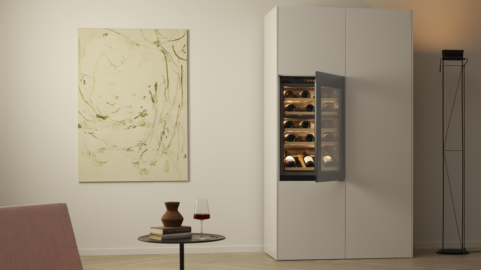 Ein stilvoller Raum mit Weinkühlschrank, Tisch mit Weinglas und abstraktem Gemälde an der Wand.