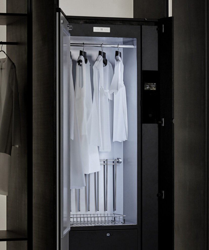 Moderner Schrank mit weißen Kleidungsstücken auf Bügeln, vermittelt Ordnung und Minimalismus.