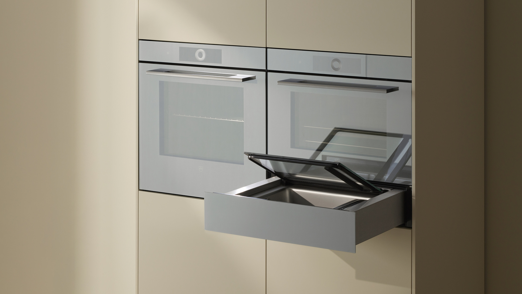 Moderne Küche mit zwei silbernen Öfen und einer herausgezogenen Glas-Schublade in beigen Schränken.