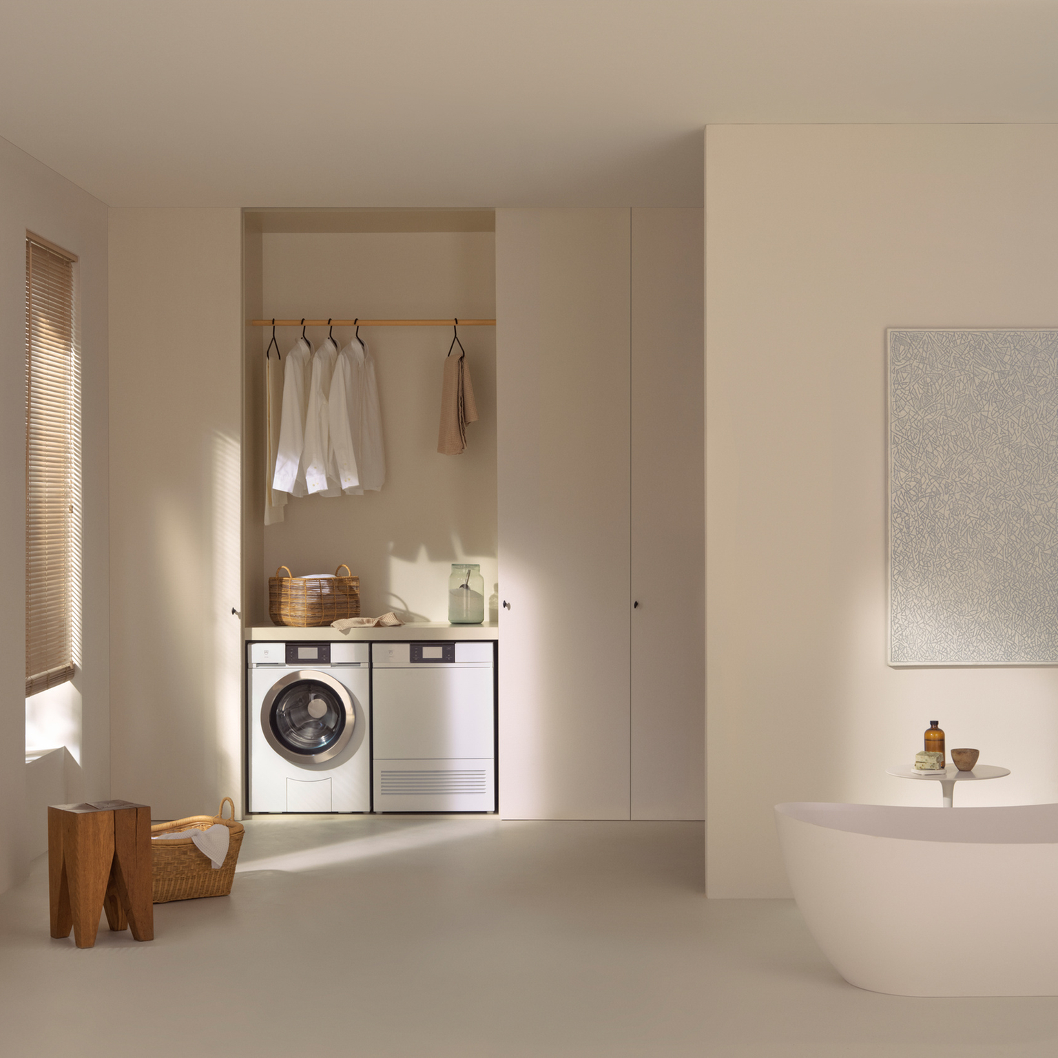 Ein modernes, minimalistisches Badezimmer mit Waschmaschine, Trockner und freistehender Badewanne.