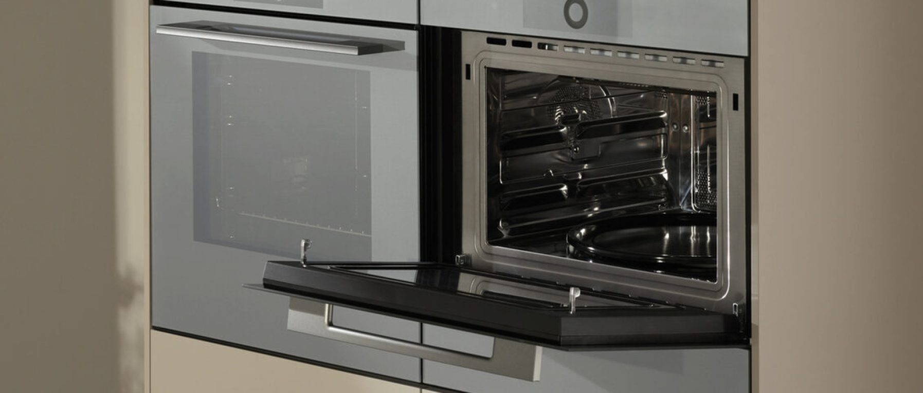 Moderner Küchenbereich mit geschlossenem Backofen und geöffneter Mikrowelle in Edelstahloptik.