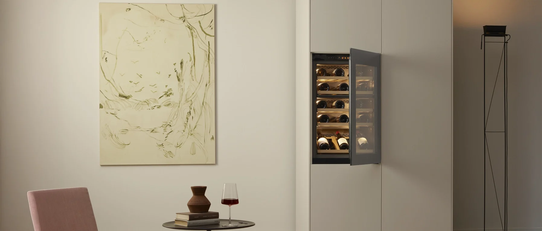 Stilvolles Interieur mit Weinkühlschrank, abstraktem Gemälde, Tisch mit Vase und Glas Rotwein.